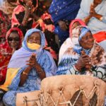 Women in vibrant traditional clothing gathered in cultural celebration setting.