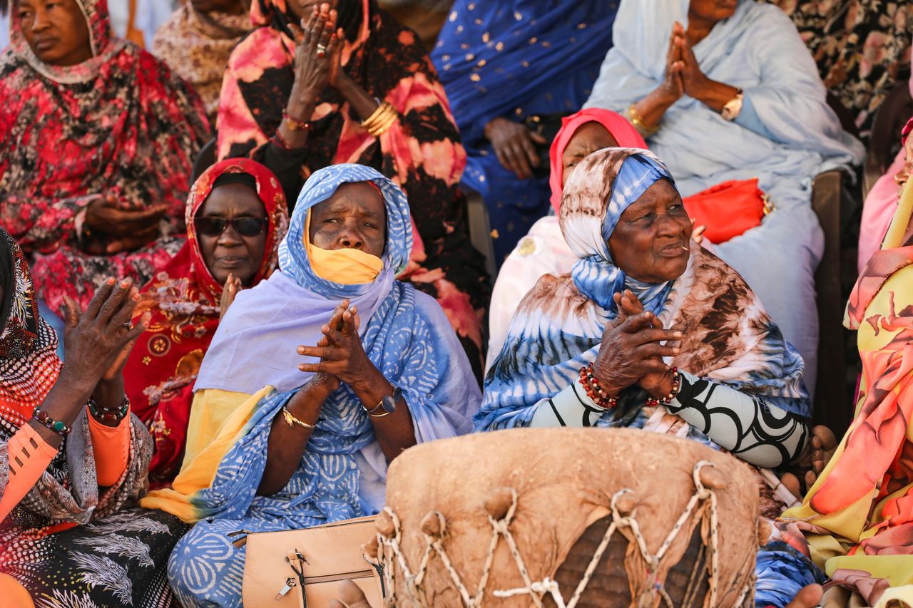 Women in vibrant traditional clothing gathered in cultural celebration setting.